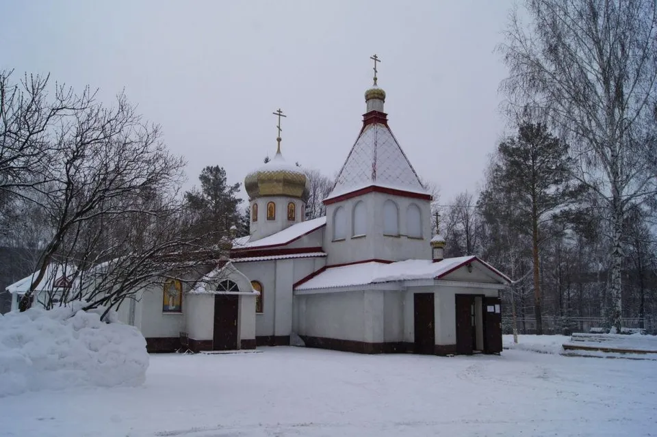 Небольшой одноглавый храм с красной кровлей и золотым куполом, вид зимой