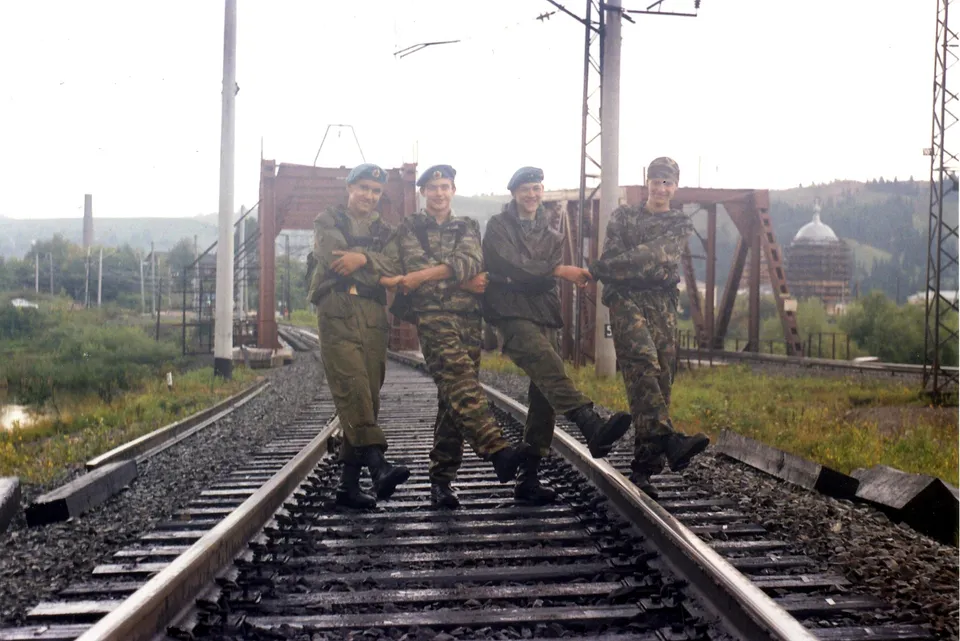 Четверо подростков в военной форме идут по железнодорожным путям